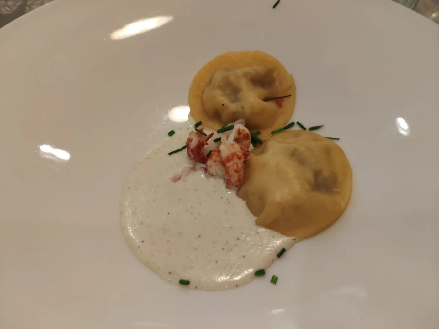 Voorbeeld van Raviolibeursjes gevuld met garnaal en peer in een saus van geitenkaas