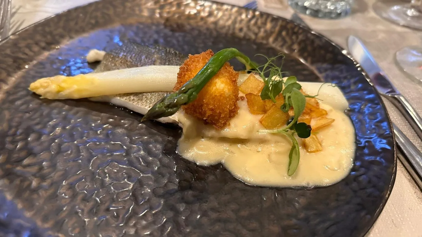 Voorbeeld van Zeebaars met een gefrituurde eidooier, gebakken groente asperge, beurre blanc saus en aardappel kaantjes