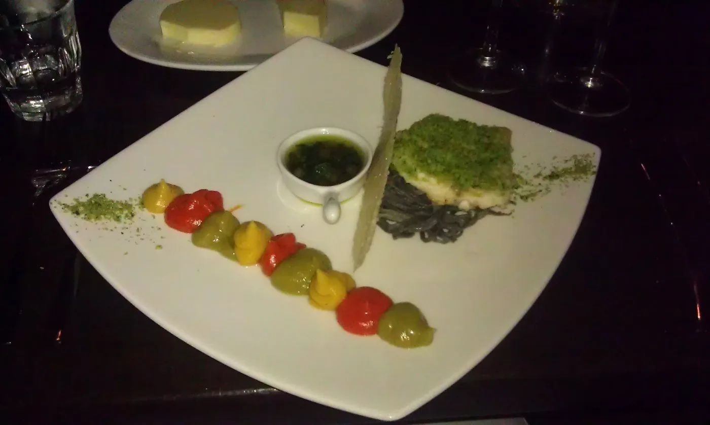 Voorbeeld van Zeebaarsfilet met crème van drie kleuren paprika, inktvis pasta en olie van ansjovis en peterselie
