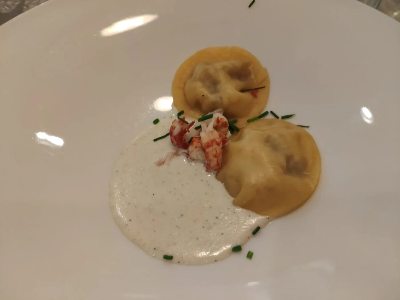 Voorbeeld van Raviolibeursjes gevuld met garnaal en peer in een saus van geitenkaas